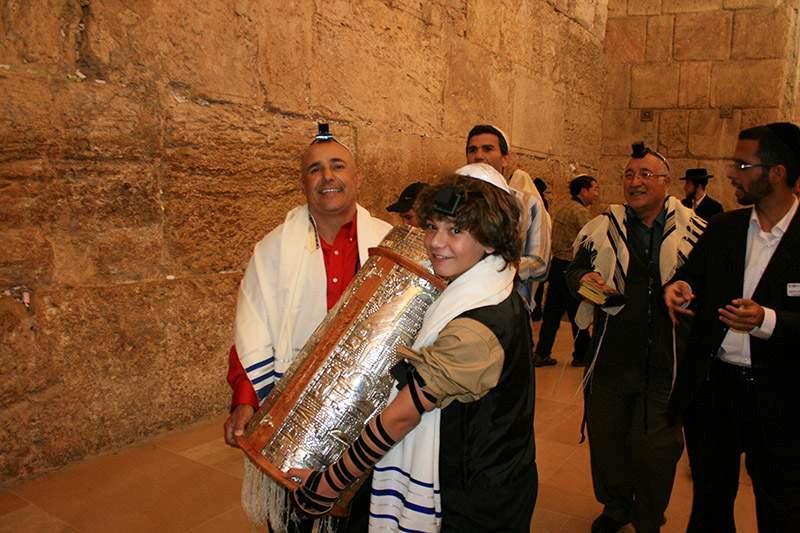 上图:一个13岁的犹太男孩在成为「诫命之子」的仪式上抱着一个经筒,里面是一卷希伯来圣经。